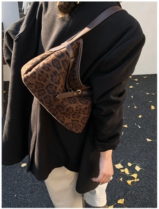 Detail of leopard print suede shoulder bag with adjustable brown leather strap on model