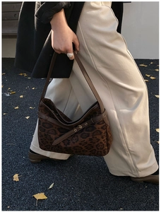 Close-up of leopard print suede shoulder bag with brown leather strap and metal buckle