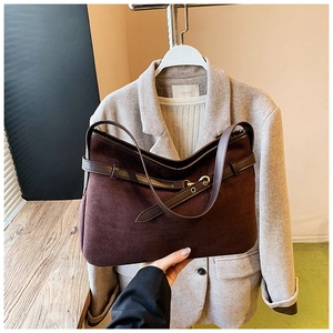 Close-up of deep brown suede tote bag with leather straps and brass buckle detail
