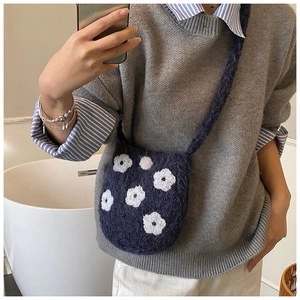 Detail of plush knit crossbody bag with white flower embroidery and soft strap