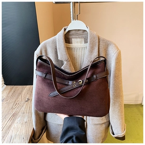 Detail of dark brown suede tote bag featuring decorative straps and metal eyelets