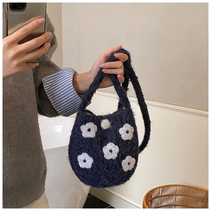 Detail of navy plush bucket bag with white floral embroidery and soft knit texture