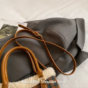 Detalle de la correa ajustable de cuero en un bolso tipo cubo de lana y cuadros