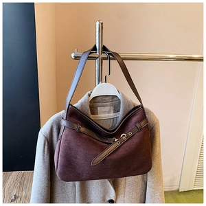 Detail view of brown suede bucket bag with leather strap and golden metal hardware
