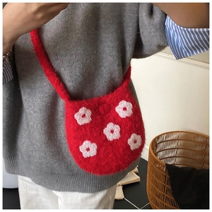 Detail of red fuzzy knit bucket bag with five white floral embroidery accents