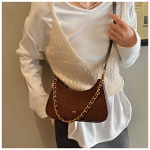Detalle del bolso hobo de ante marrón oscuro con cadena dorada y correa de cuero