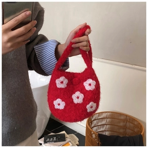 Close-up of red plush bucket bag with white floral embroidery and soft furry texture