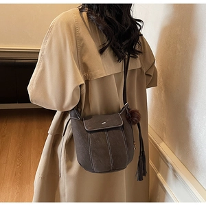 Dettaglio della borsa a tracolla vintage marrone con cuciture a contrasto e nappa decorativa