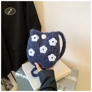 Detail of navy blue plush bucket bag with white floral embroidery and cat ear design