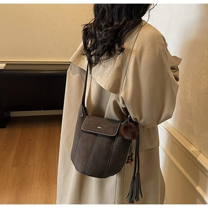 Dettaglio della borsa a secchiello opaca vintage con pompon e nappa su un cappotto caldo