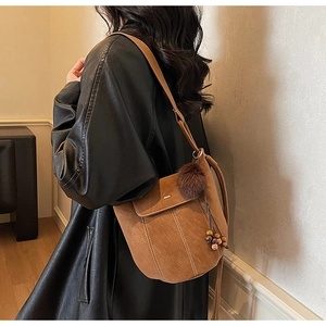 Borsa a secchiello in camoscio marrone opaco con pompon e perline in legno sulla tracolla