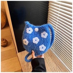 Close-up of blue plush bucket bag featuring 3D white floral embroidery and cat ear design