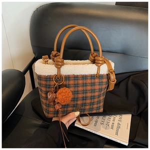 Détail du sac à carreaux avec bordure en peluche et poignée en cuir marron à nœud