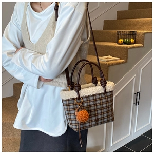 Détail d'un sac à main à carreaux avec bordure en fausse fourrure et pompon orange