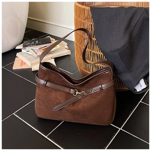 Detail of coffee brown suede bucket bag with decorative eyelet strap and metal hook