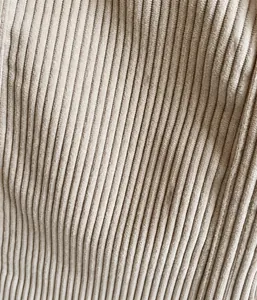 Makroaufnahme von cremefarbenem Cordstoff mit dicker vertikaler Struktur und weichem Material