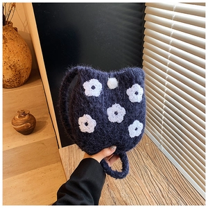 Detail of navy blue fuzzy bucket bag with white floral embroidery and bead closure