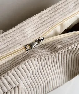 Detail der Cord-Struktur mit glattem Metallreißverschluss an weißer Schultertasche