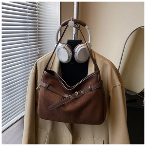 Detailed close-up of dark brown suede tote bag with leather belt and golden hardware