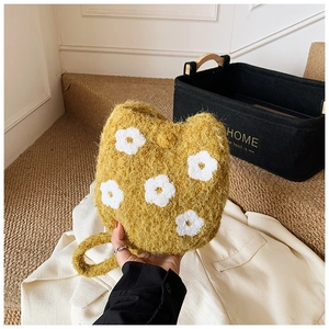 Detail of soft yellow plush bucket bag featuring white flower embroidery and fuzzy texture