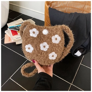 Close-up of soft brown plush bucket bag featuring detailed white 3D floral embroidery