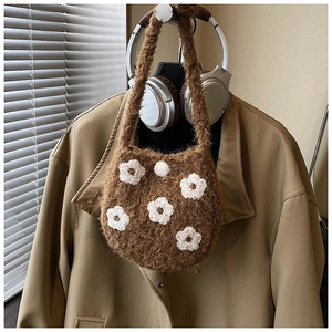 Close-up of brown plush bucket bag with white floral embroidery and knitted texture