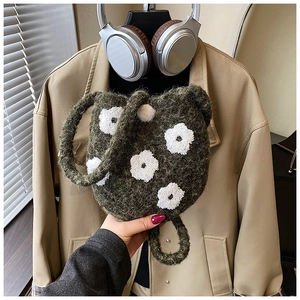 Detailed close-up of dark green plush bucket bag with white floral embroidery for winter