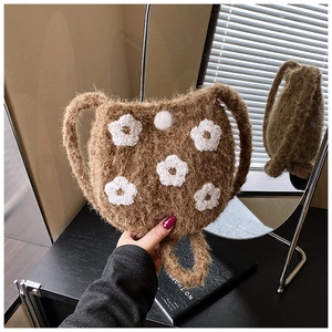 Close-up of brown plush bucket bag with white embroidered 3D flowers and fuzzy texture
