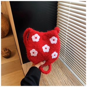 Close-up of red plush bucket bag featuring white flower embroidery and soft faux fur texture