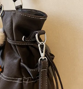 Close-up of brown litchi leather texture with white contrast stitching and silver hook