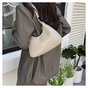 Detailansicht der beigen Halbmond-Tasche mit feinen Nähten und verstellbarem Schultergurt
