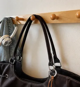 Close-up of dark brown tote bag with white contrast stitching and silver metal hardware