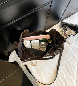 Top view of spacious dark brown tote bag interior with tablet and daily essentials