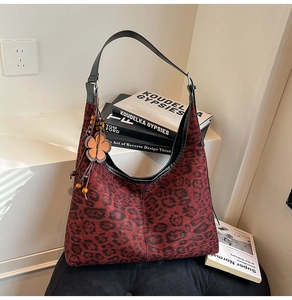 Detalle de bolso hobo con estampado de leopardo rojo oscuro y colgante de flor étnica