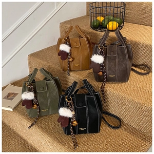Detail of four colorful suede bucket bags with contrast stitching and glove charms