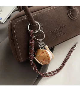 Close-up of baseball glove, ball and bat keychain charms on a brown textured handbag