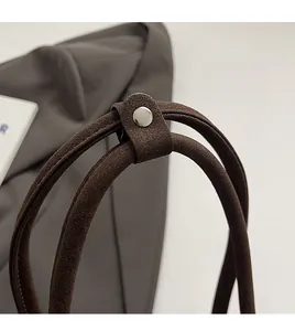 Close-up of dual rope handles with silver rivet on dark coffee faux suede bag