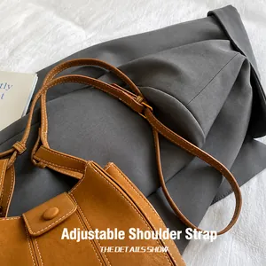 Detail of adjustable brown suede shoulder strap with precise white double stitching and metal buckle