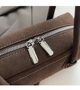 Close-up of smooth silver dual zippers and fine stitching on brown suede shoulder bag
