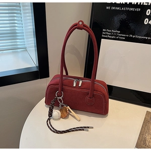 Detail view of burgundy frosted leather bag with baseball charms and textured logo