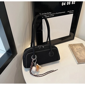 Detail of black faux leather tote with double zippers and unique baseball charm pendant