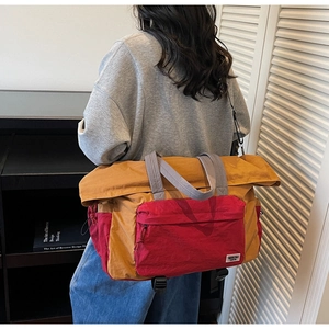 Detailed view of color-block canvas travel bag with ginger red panels and shoulder strap
