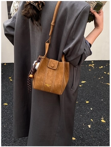 Brown suede bucket bag detail with contrast stitching and floral scarf accessory