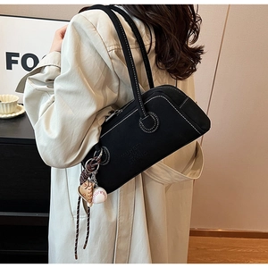 Detail of retro black matte shoulder bag with white contrast stitching and baseball charm