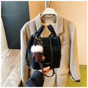 Detail of black bucket bag with white contrast stitching and unique creative charm accessory