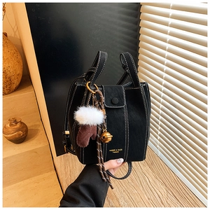 Detail of black bucket bag with contrast stitching and festive charm on wood background