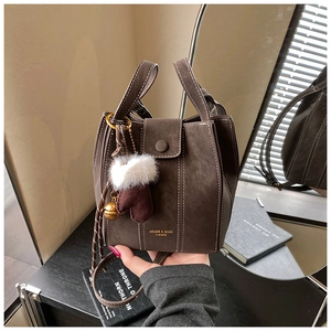 Detail of dark brown bucket bag with white stitching and decorative glove charm