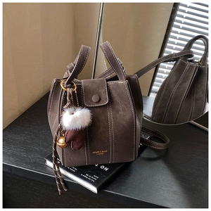 Detail of dark brown bucket bag featuring contrast stitching and a winter glove charm