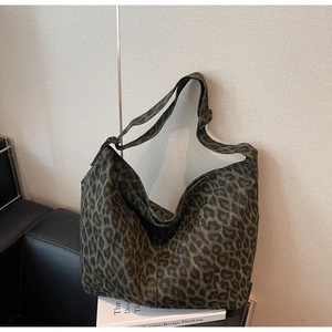 Détail du sac cabas en toile à imprimé léopard avec bandoulière large réglable sur canapé