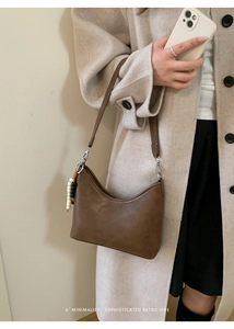 Detail view of brown semi-moon bucket bag with retro bead charm and silver hardware